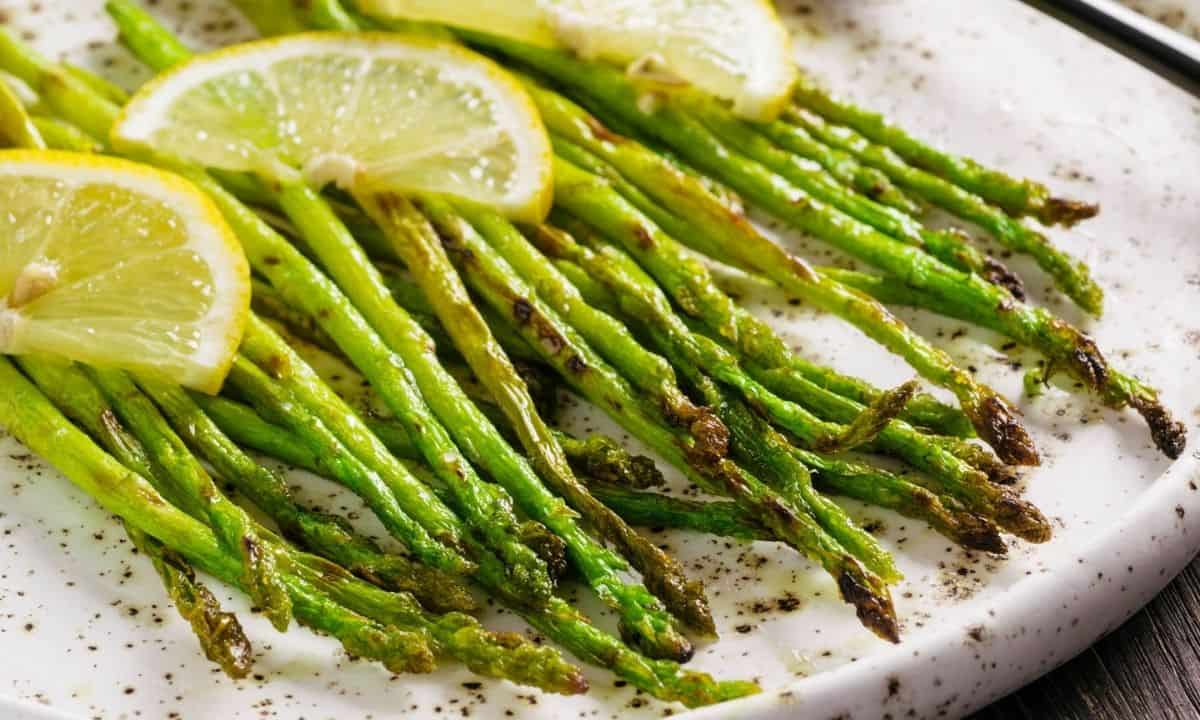 roasted asparagus with lemon slices in a white dish
