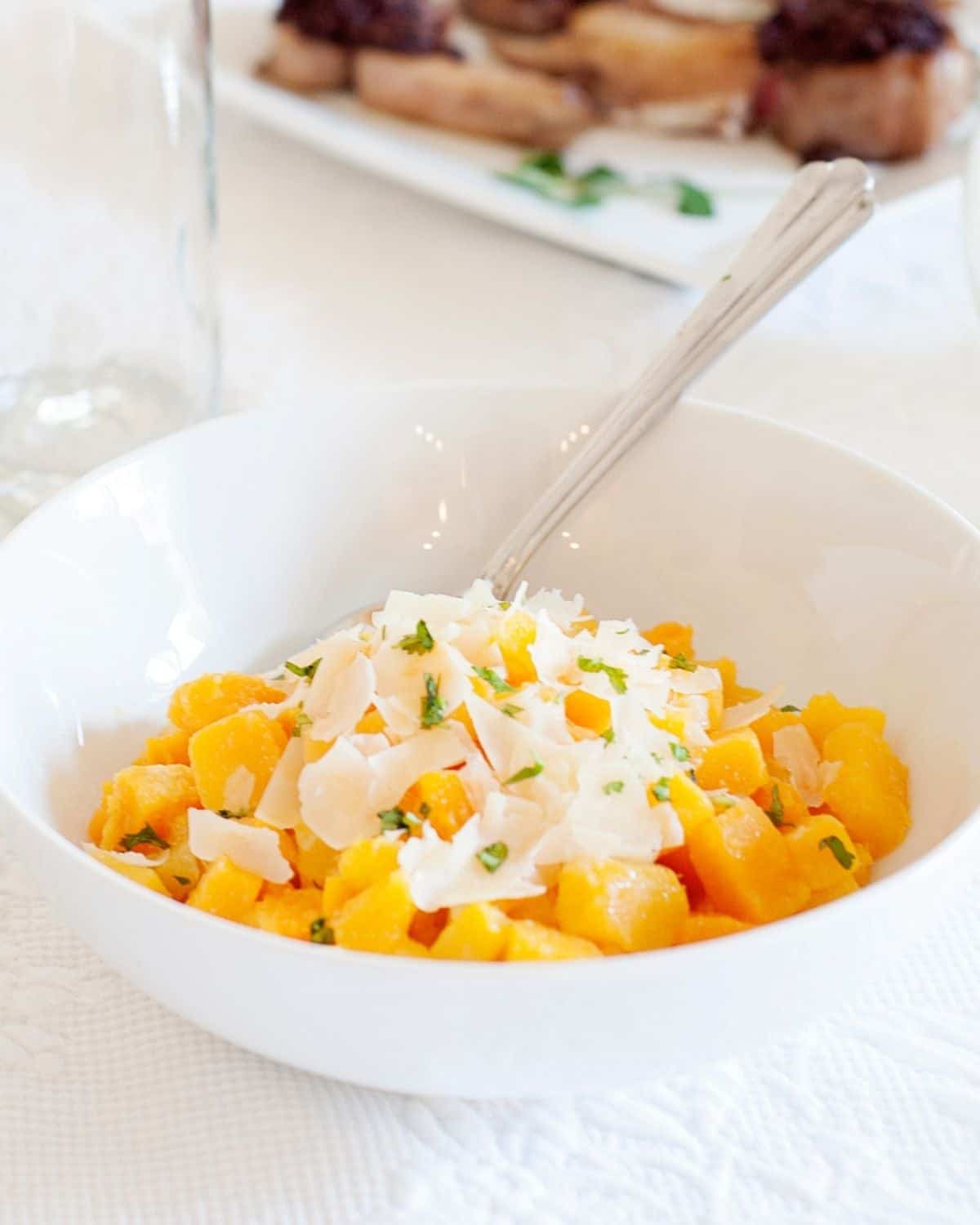 a bowl of savory butternut squash cubes with Parmesan