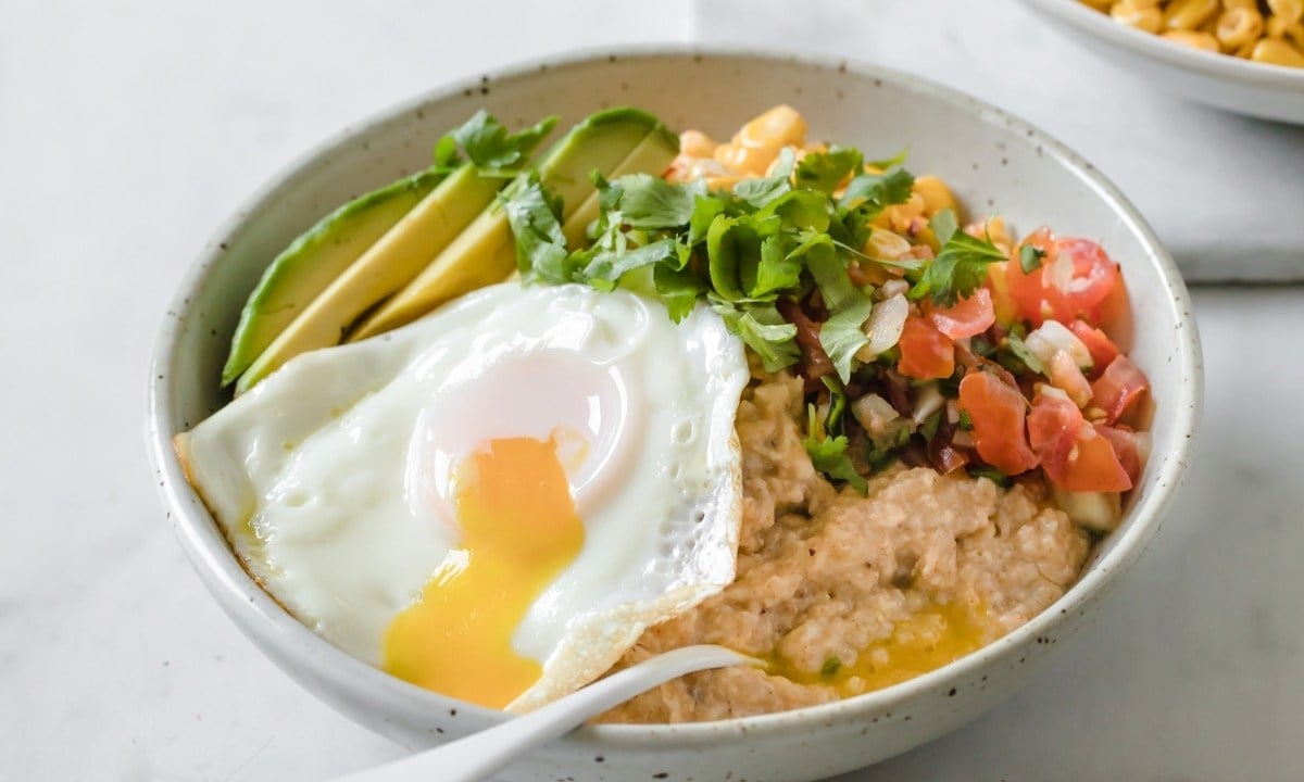 bowl of savory oatmeal with a fried egg, avocado, and pico de gallo