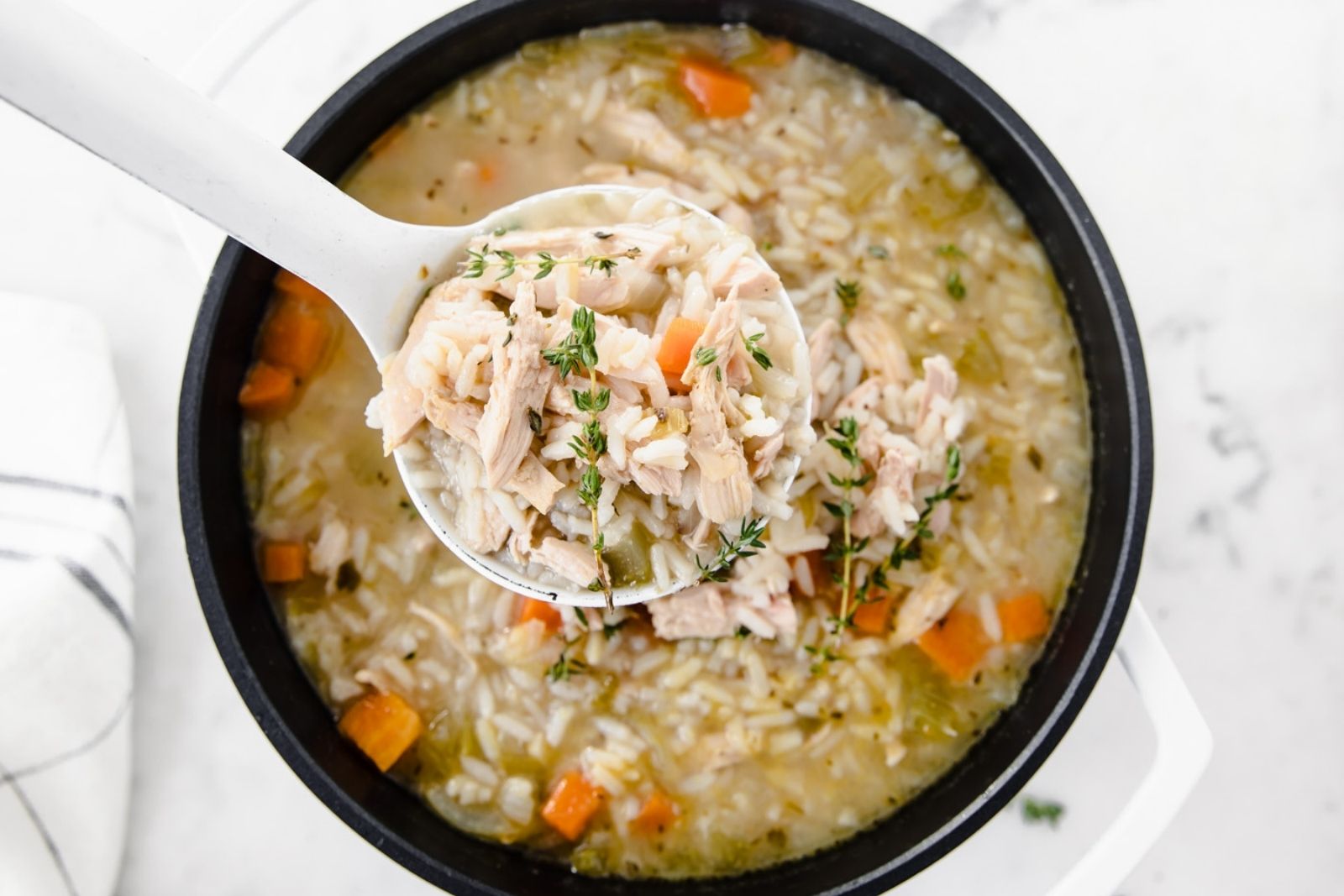 large pot of turkey and rice soup with a large spoonful of soup