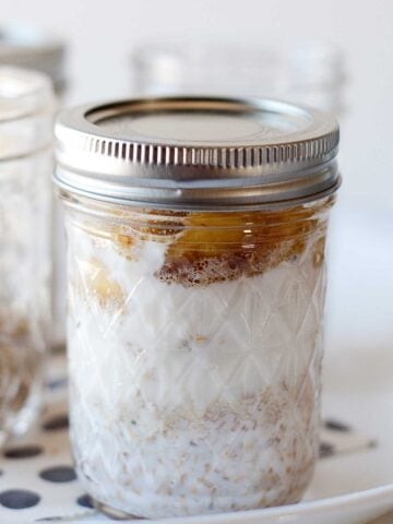 a mason jar on a plate filled with bananas foster overnight oats with steel cut oats