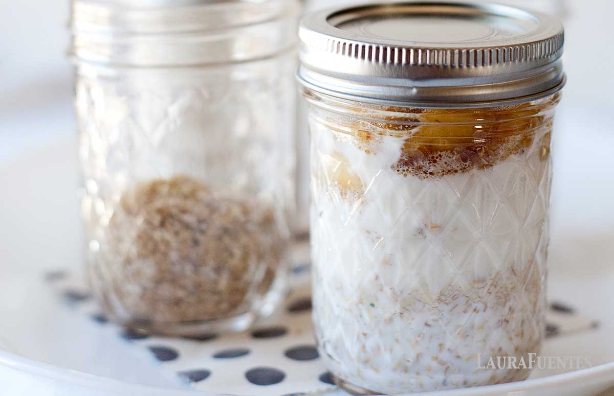 four mason jars on a plate filled with bananas foster overnight oats with steel cut oats