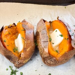 two baked sweet potatoes split in half topped with butter.