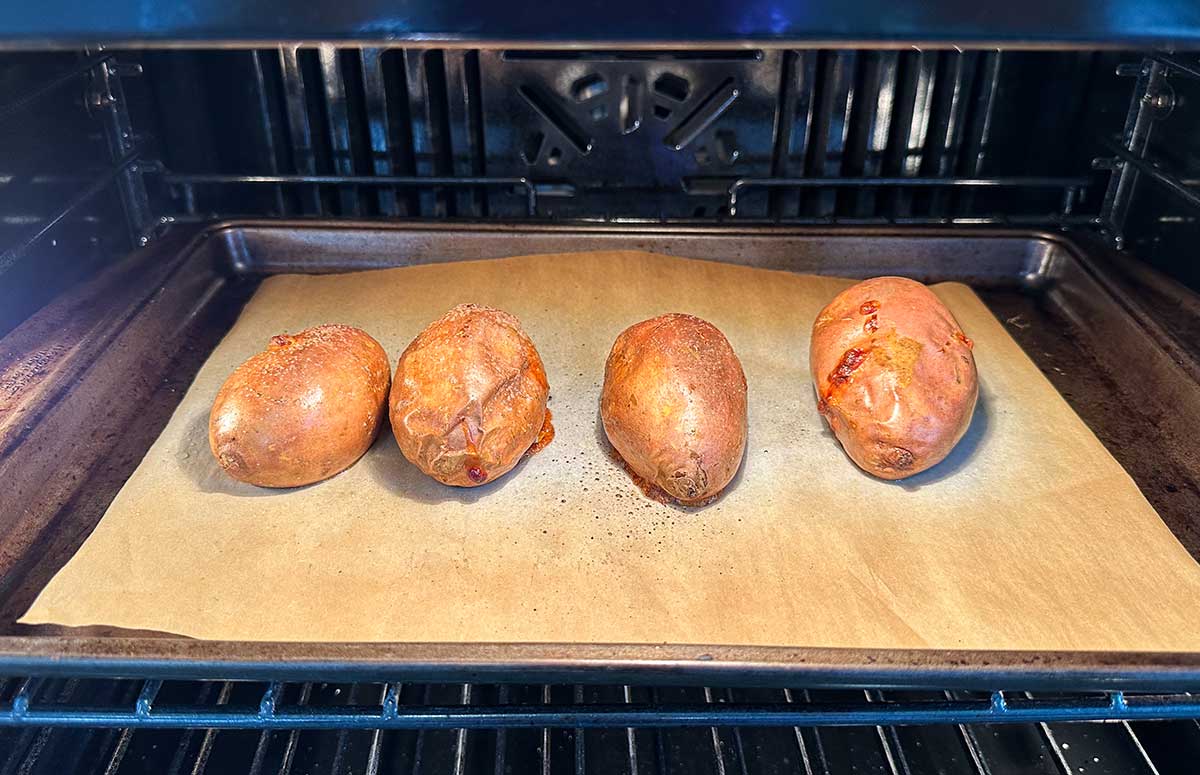 sweet potatoes baking on a sheet pan in the oven