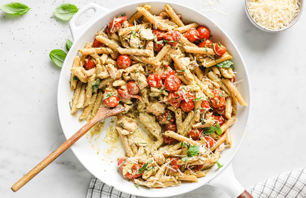 salmon pesto pasta cooking in a white skillet