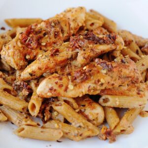 creamy sun dried tomato chicken pasta on a white plate