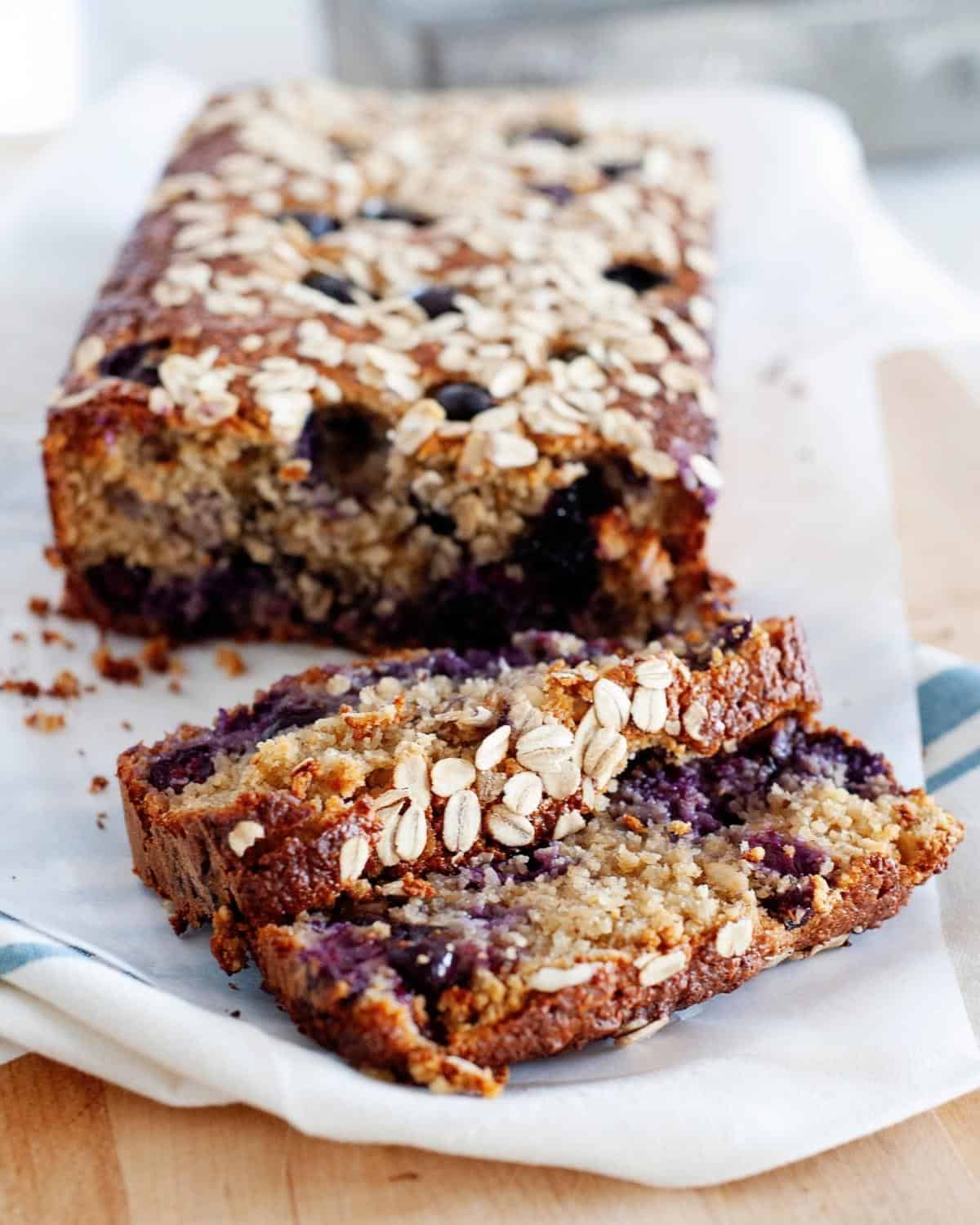 blueberry oat breakfast bread loaf; two slices cut in front of the loaf