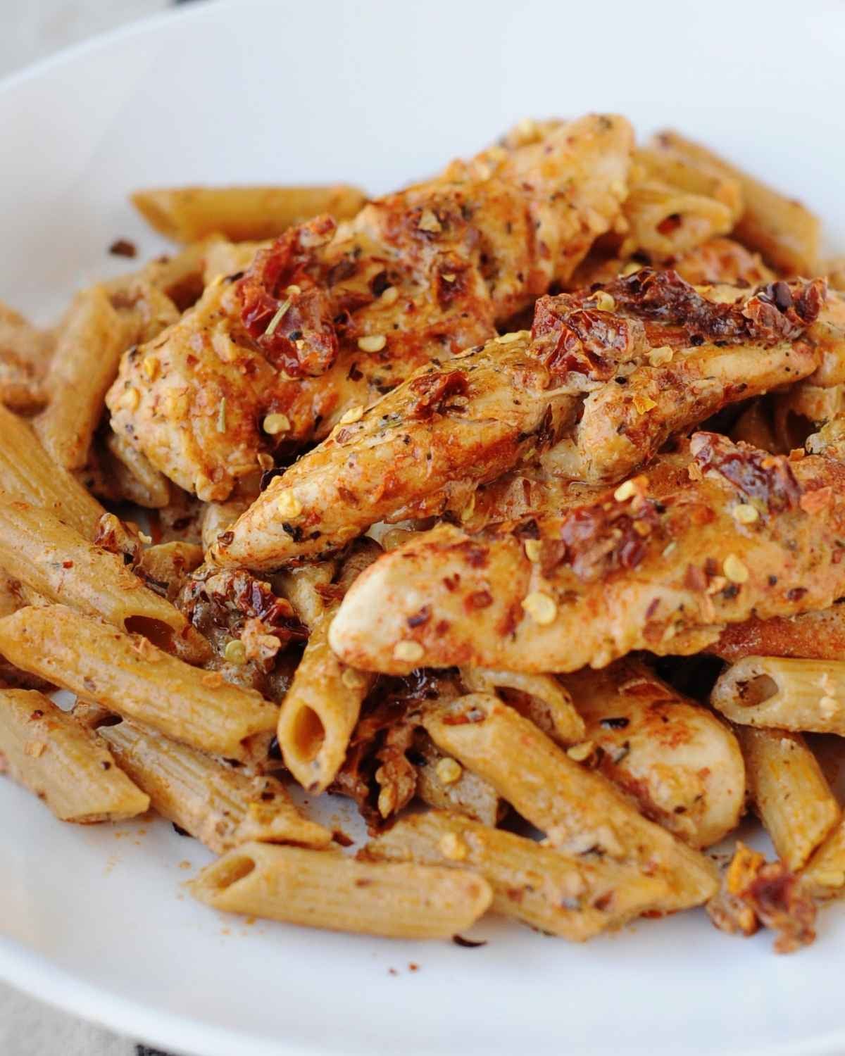 sun dried tomato pasta with chicken on a white plate