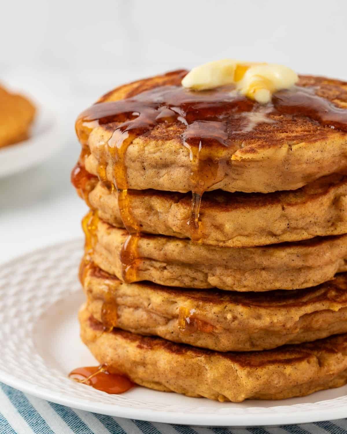 front view of a fluffy stack of healthy pumpkin pancakes topped with butter and syrup