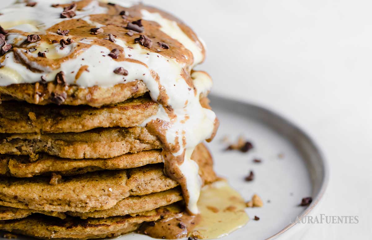 closeup of 7 pancakes stacked. Topped with whipped cream, syrup and chocolate shavings.