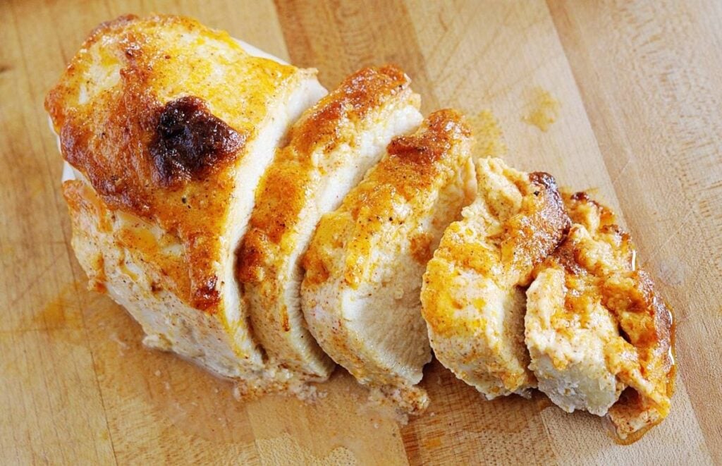 chicken breast, sliced on a cutting board. 