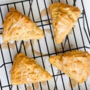 four pumpkin scones with glaze on a cooling rack