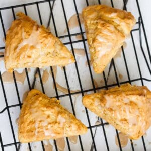 four pumpkin scones with glaze on a cooling rack