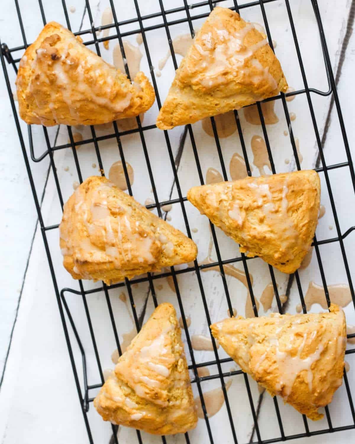 six pumpkin scones with glaze on a cooling rack
