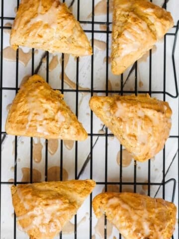 six pumpkin scones with glaze on a cooling rack
