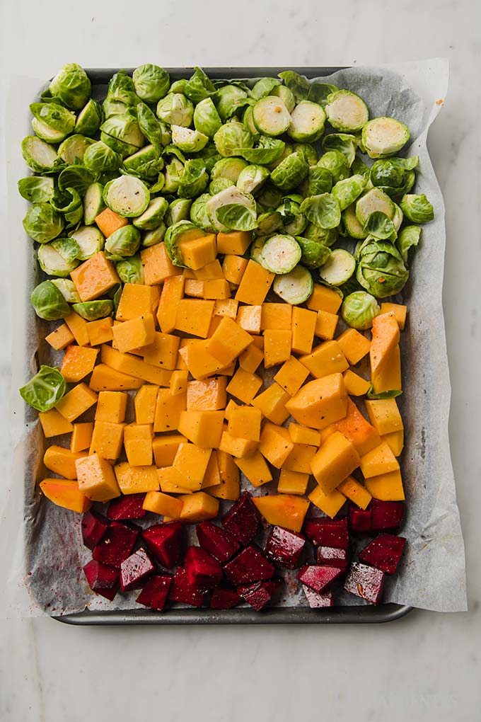 large baking sheet topped with chopped Fall vegetables arranged in three rows