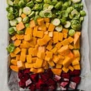 a baking sheet filled with chopped beets, butternut squash and halved Brussels sprouts.