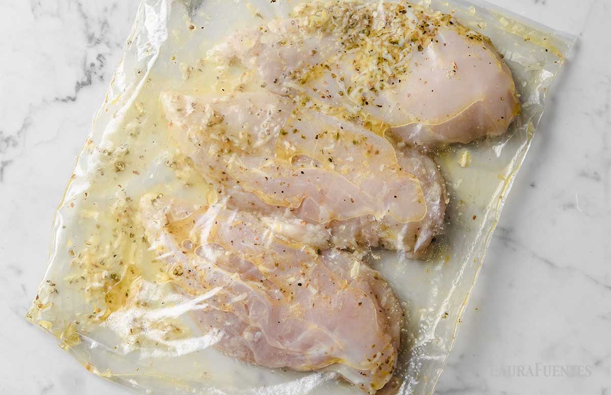 three chicken breasts marinating in a zip bag 