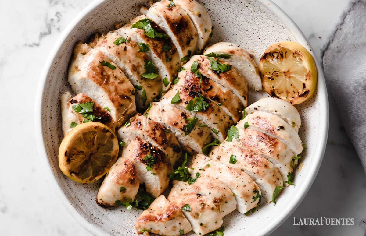 three baked chicken breasts sliced and in a bowl 