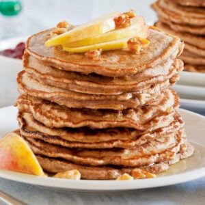stack of whole wheat pancakes topped with sliced apples