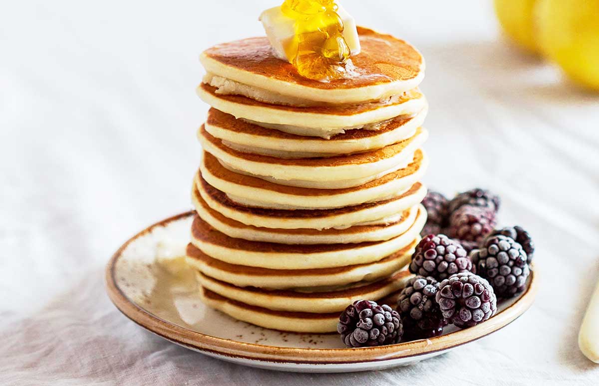 stack of pancakes made with protein powder on a plate with blackberries