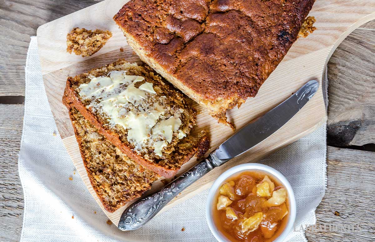overhead look at half a loaf of applesauce bread, partially sliced with butter topping