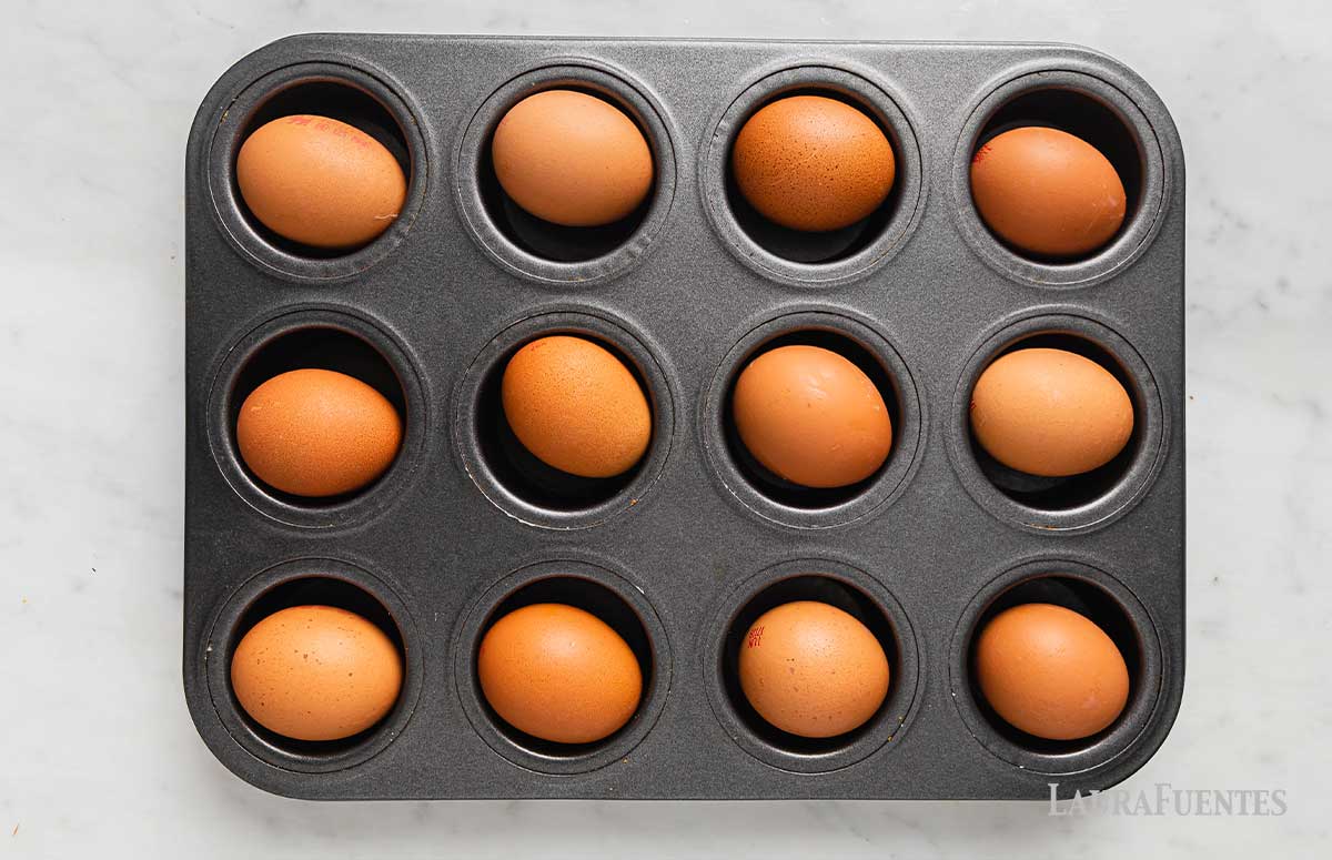 a dozen brown eggs in a muffin tin