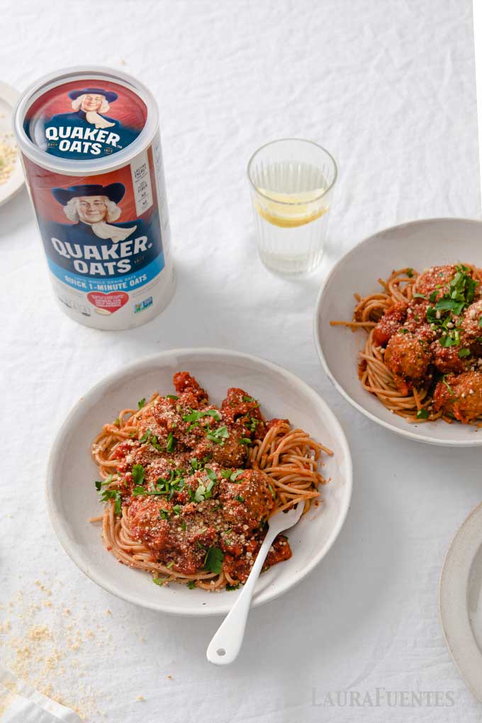 two plates of spaghetti and meatless meatballs next to can of quaker oats