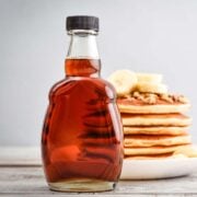 bottle of homemade pancake syrup in front of a large stack of pancakes