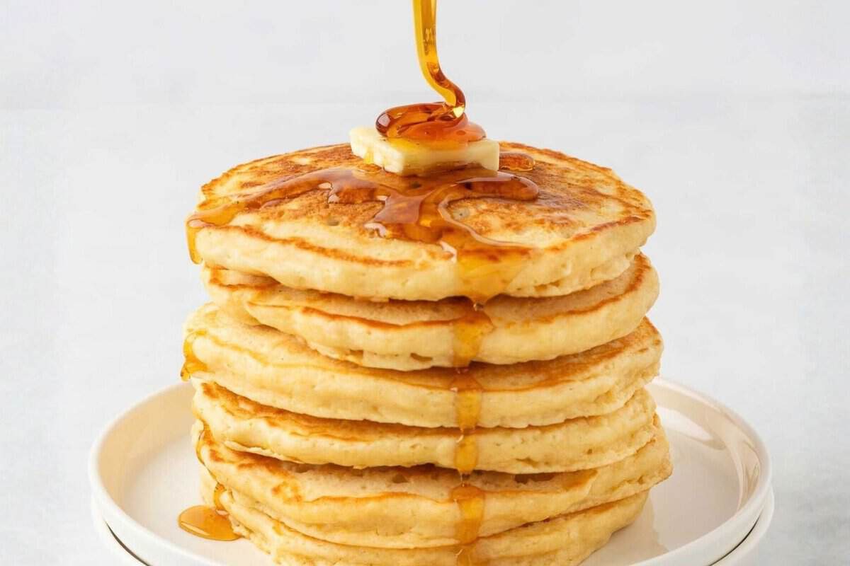 a stack of pancakes being drizzled with syrup