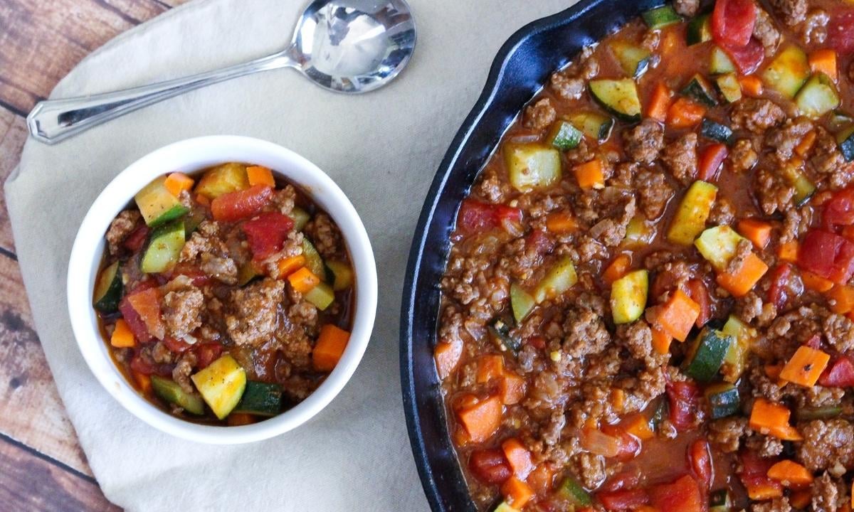 a large pot with a bowl of ground beef chili and a serving on the side