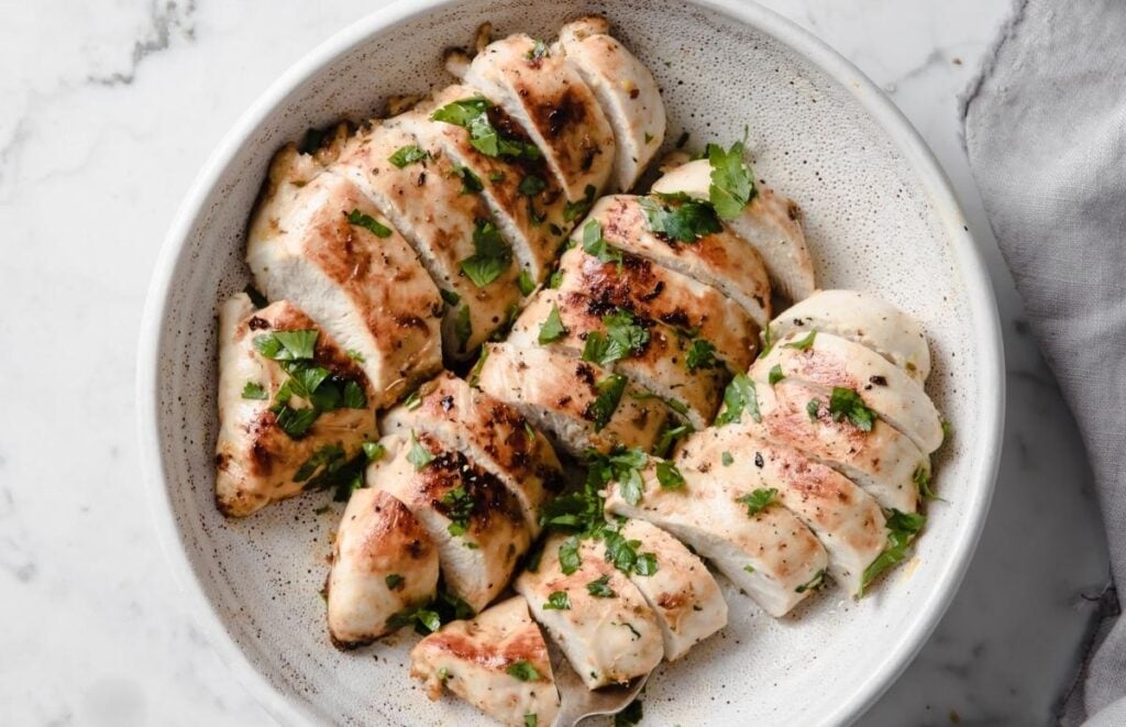 three sliced chicken breasts in a shallow bowl