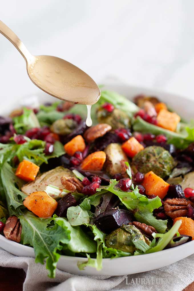 pouring dressing over winter salad with a spoon