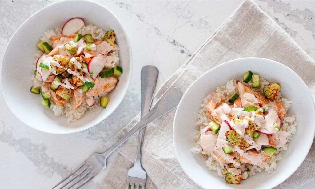two avocado salmon bowls with cucumber and rice