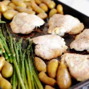 baking sheet with chicken thighs, potatoes, and asparagus
