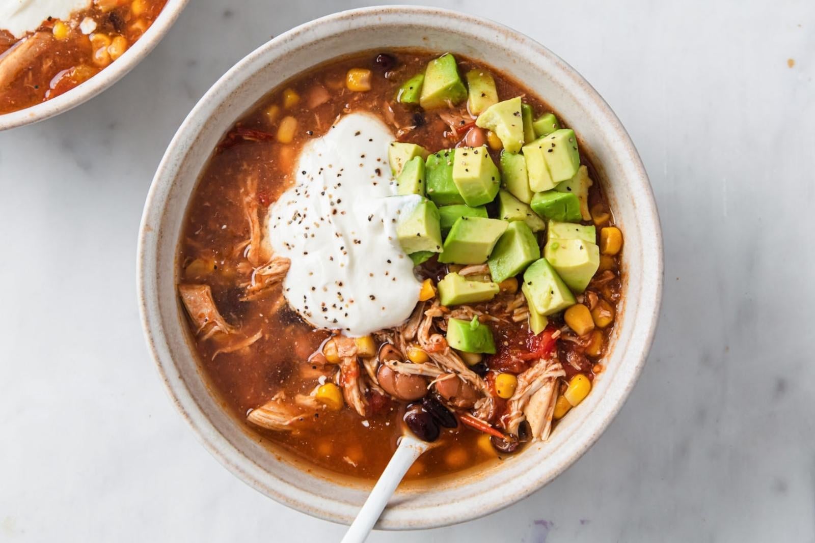 top view of a chicken taco soup topped sour cream and avocado