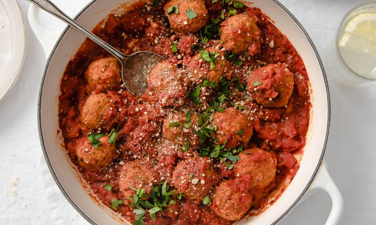 large pan of meatless meatballs next to dish of cooked spaghetti noodles