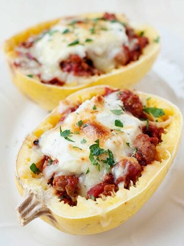 two spaghetti squash halves stuffed with lasagna and melted cheese