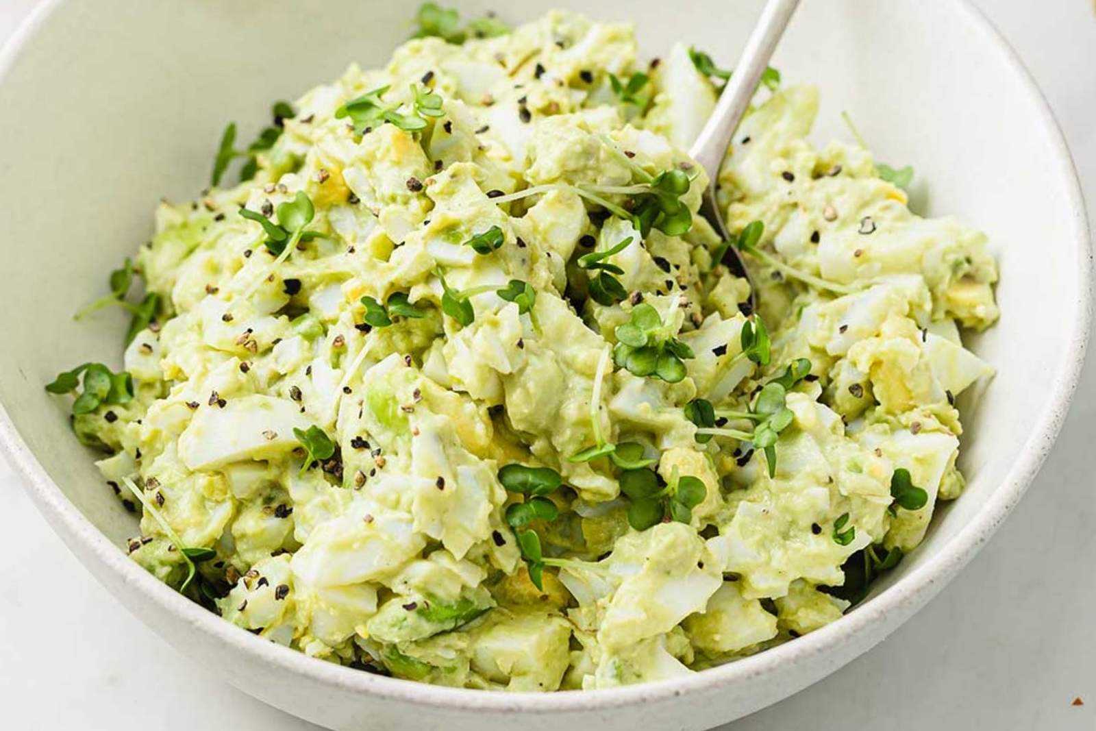 a white bowl with avocado egg salad