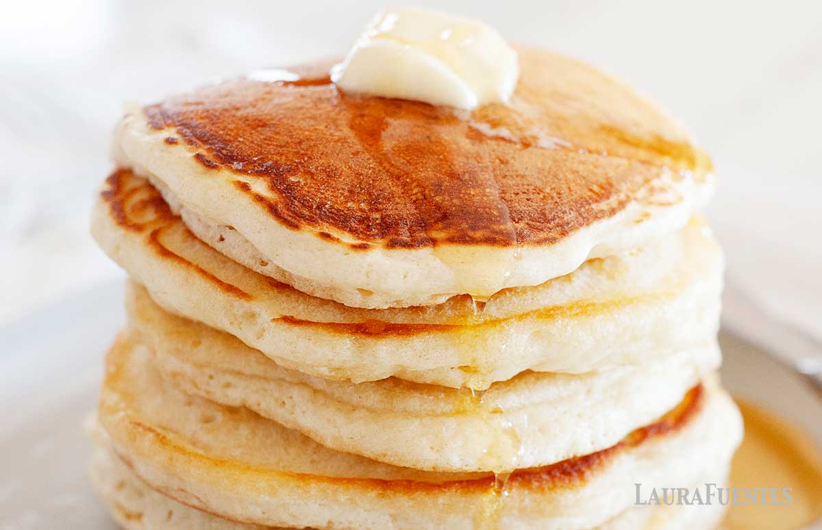 Stack of pancakes topped with butter and syrup.