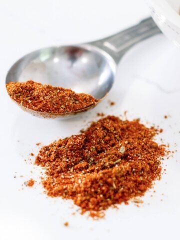 creole seasoning spilled on a countertop with a large tablespoon