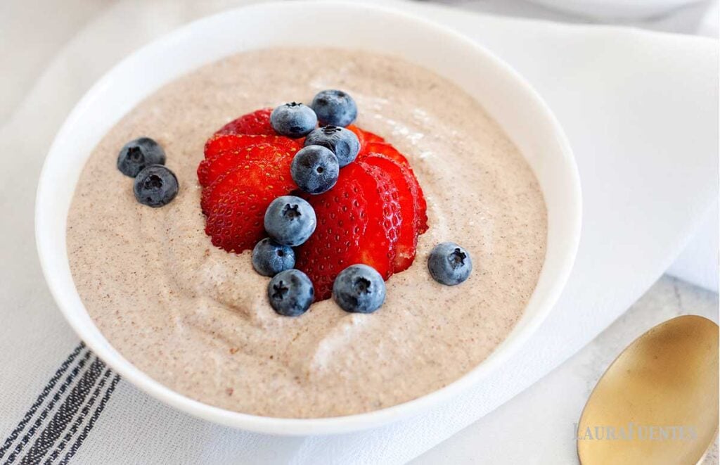 a bowl of grain free oatmeal topped with blueberries and strawberries 