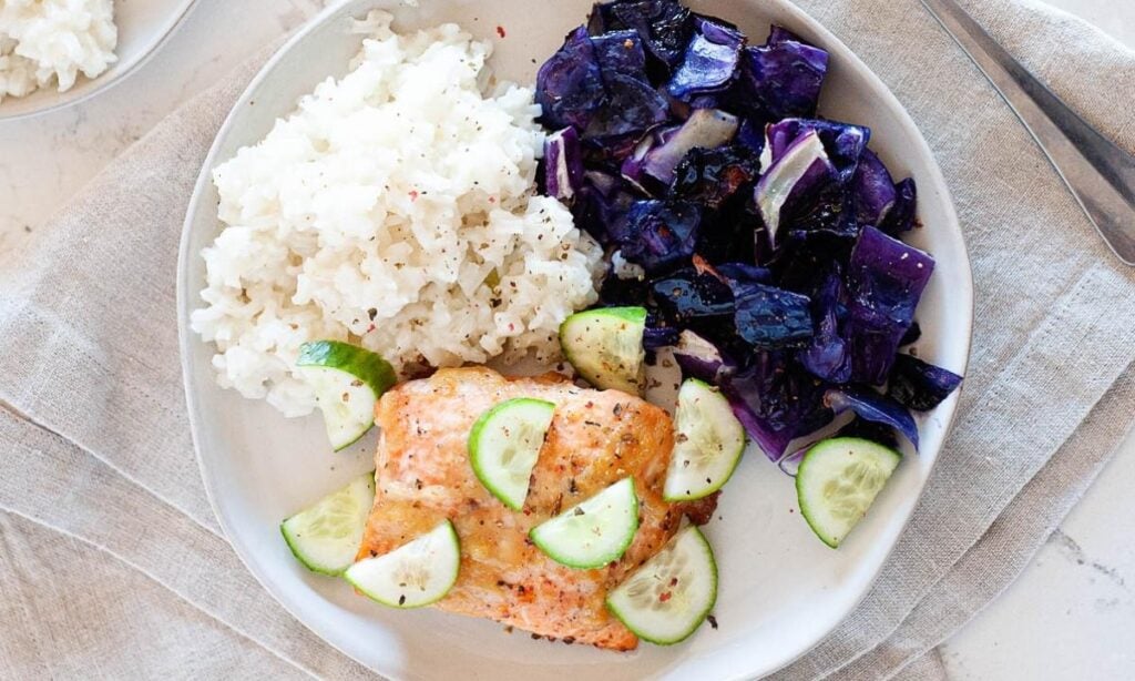 salmon, cabbage, rice and cucumber slices on a plate