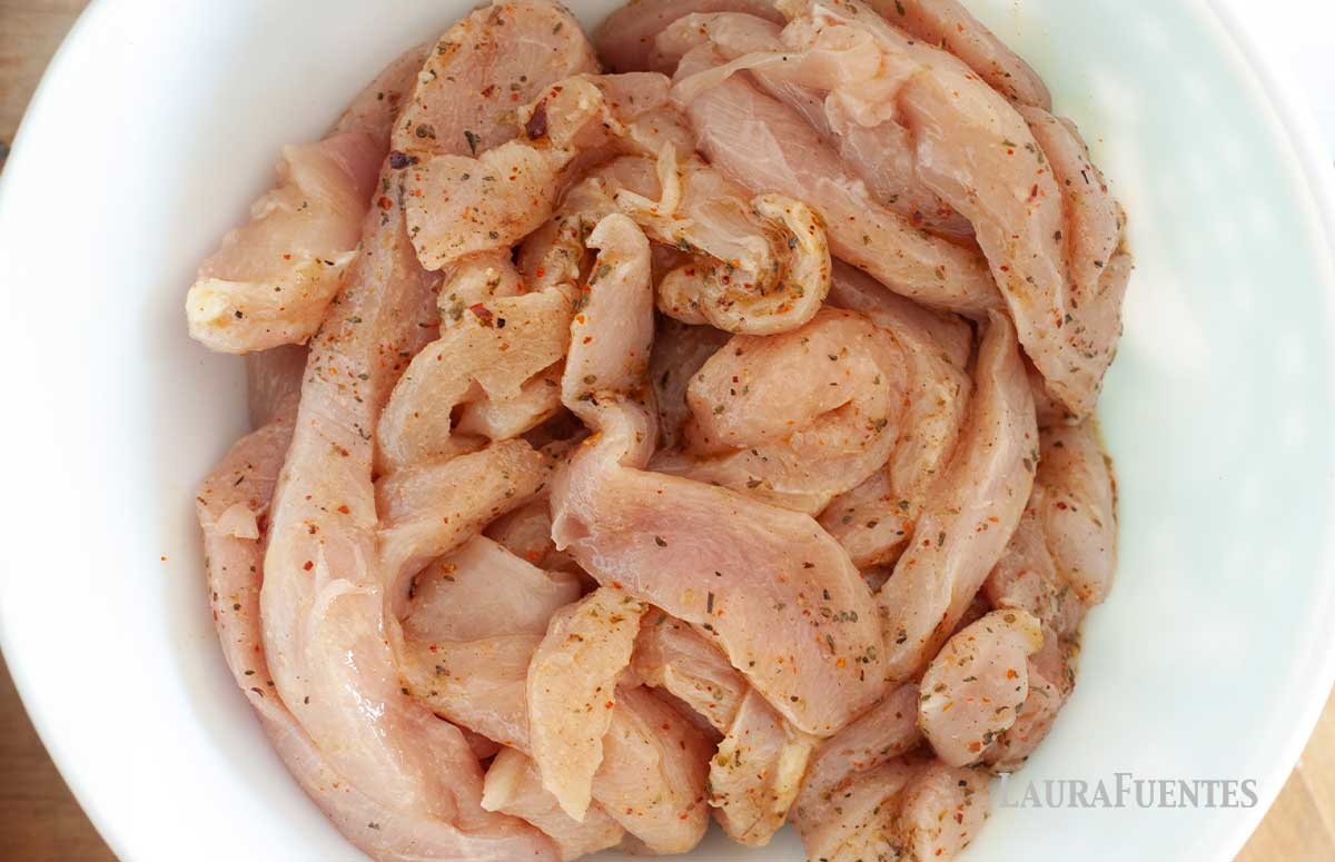 large bowl of chicken strips being marinated for fajitas