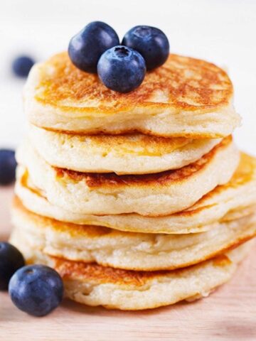 stack of low carb coconut flour pancakes stacked to how size topped with blueberries