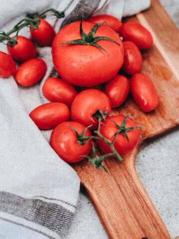 freshly washed tomatoes on a cutting board