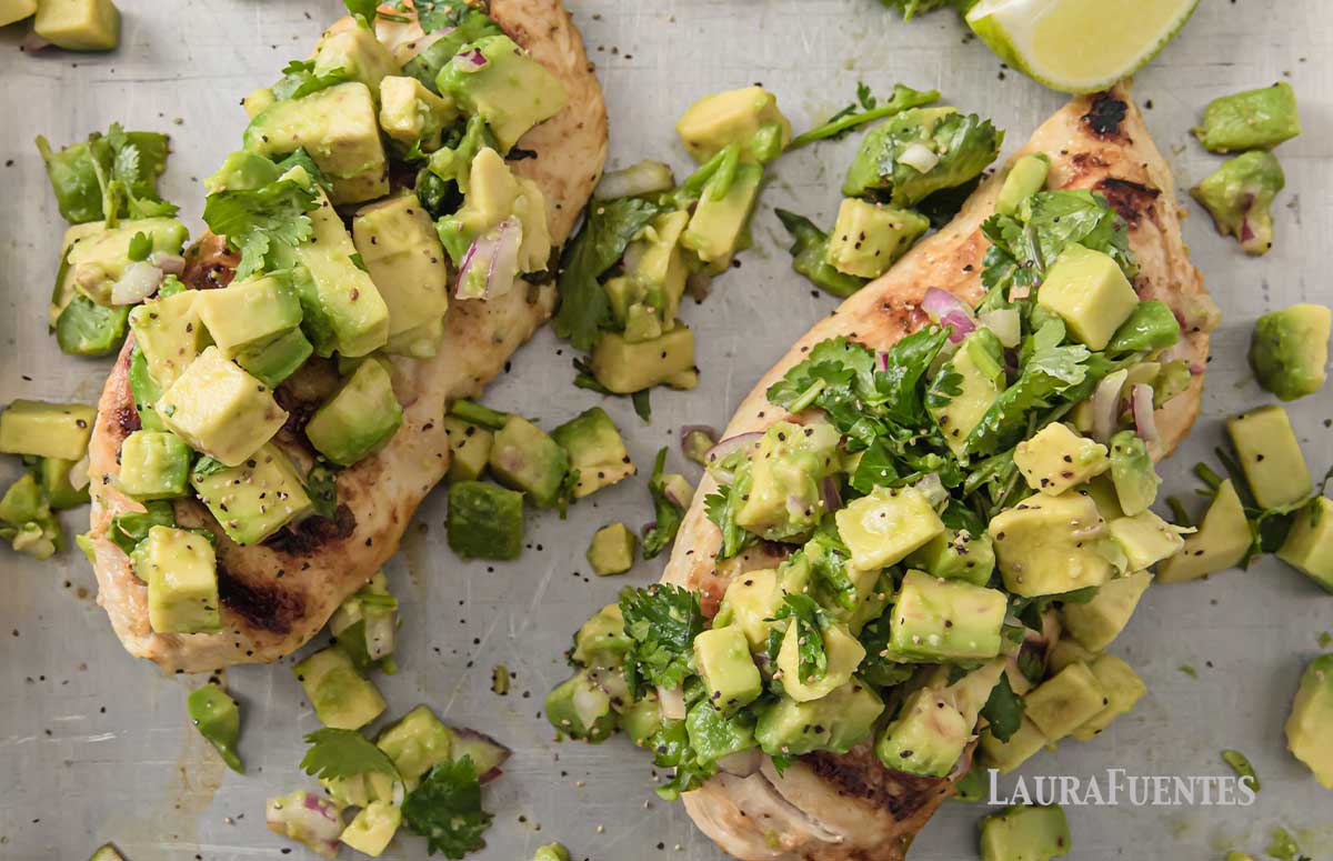 closeup of two chicken breasts topped with avocado salsa