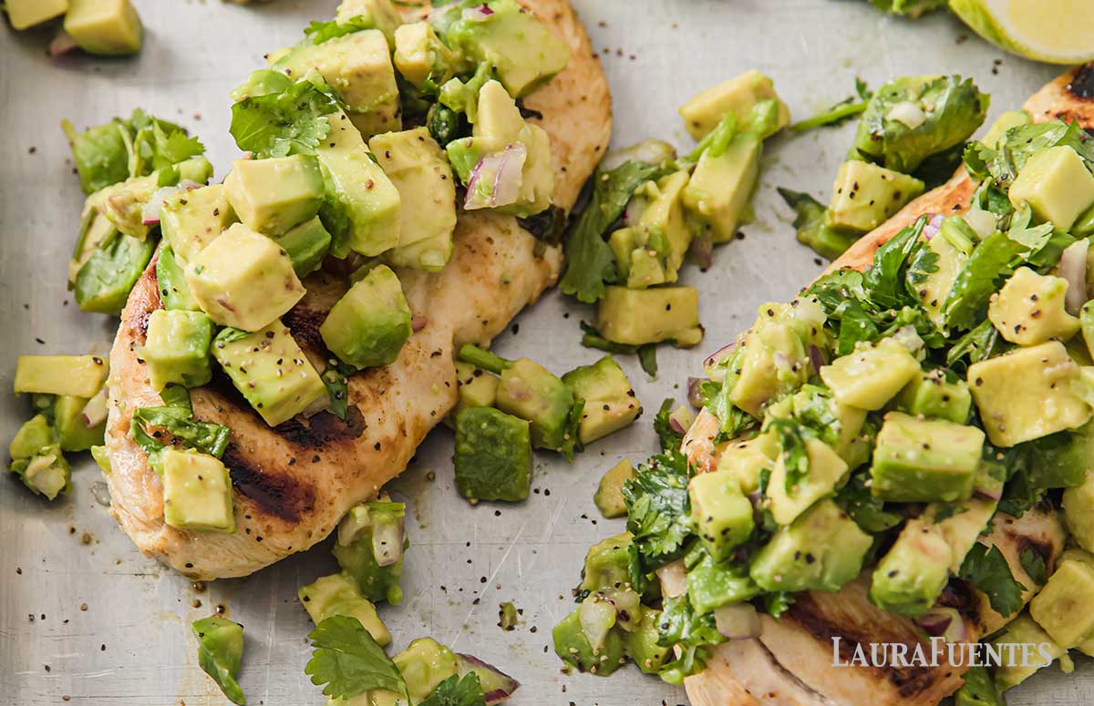marinated chicken breasts on a sheet pan topped with avocado salsa