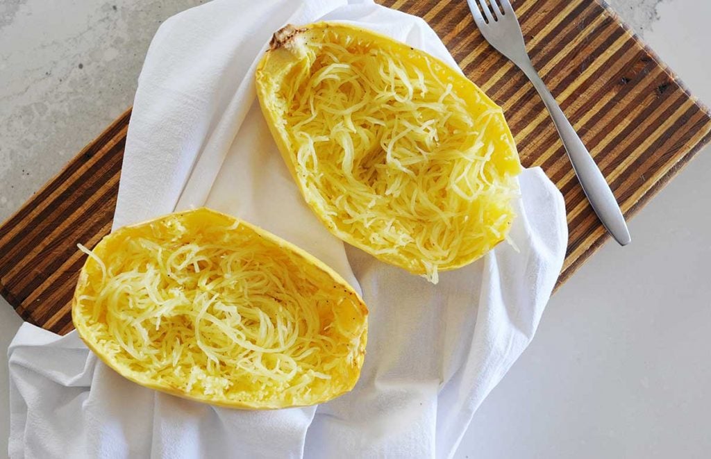 two spaghetti squash halves with squash made into "noodles" inside the skin.