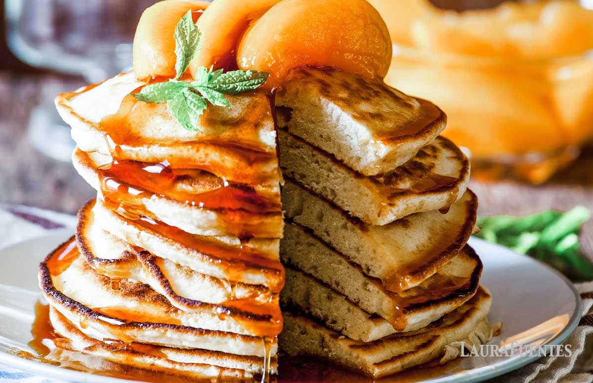 large stack of pancakes topped with peach slices